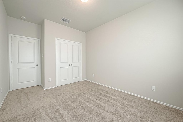 unfurnished bedroom with light colored carpet and a closet