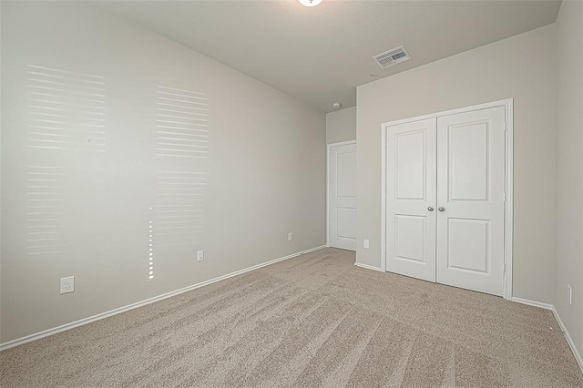 unfurnished bedroom featuring light carpet and a closet