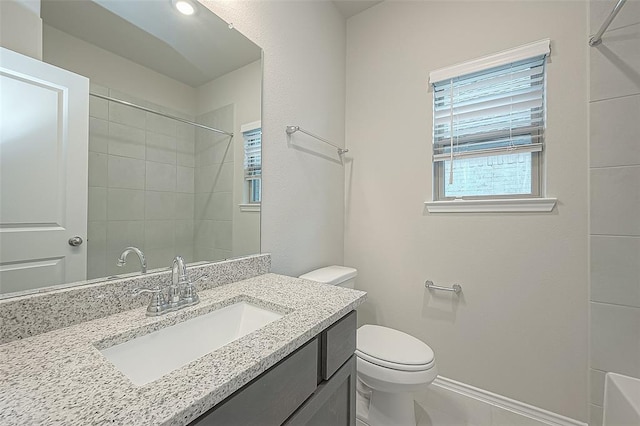 bathroom with vanity, toilet, and a tile shower