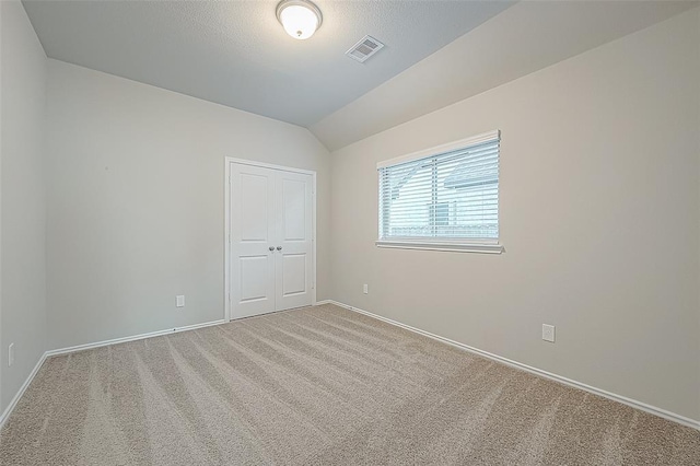 carpeted empty room featuring vaulted ceiling