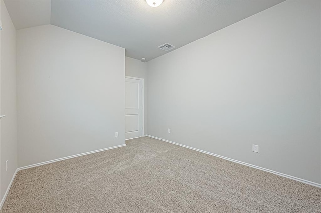 unfurnished room featuring lofted ceiling and light colored carpet