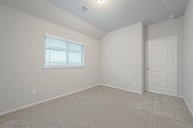 carpeted empty room with vaulted ceiling