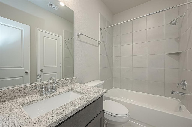 full bathroom featuring vanity, tiled shower / bath, and toilet