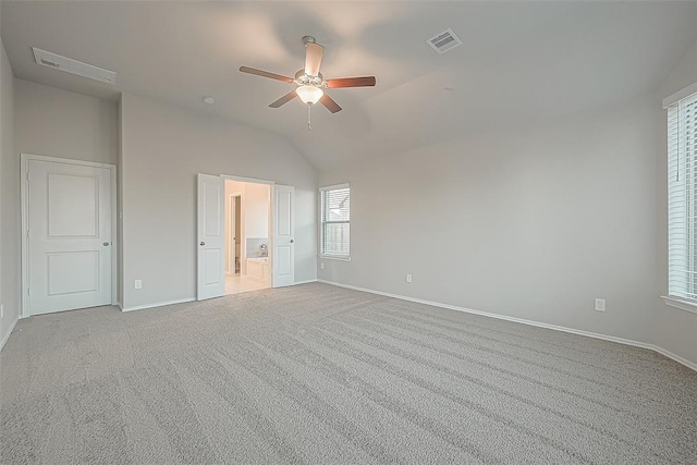 unfurnished bedroom featuring vaulted ceiling, light colored carpet, ceiling fan, and ensuite bathroom