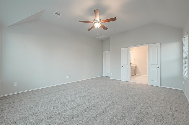 unfurnished bedroom featuring vaulted ceiling, light colored carpet, ceiling fan, and ensuite bathroom