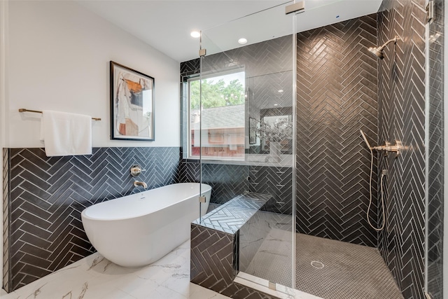 full bath featuring a soaking tub, marble finish floor, a stall shower, and tile walls