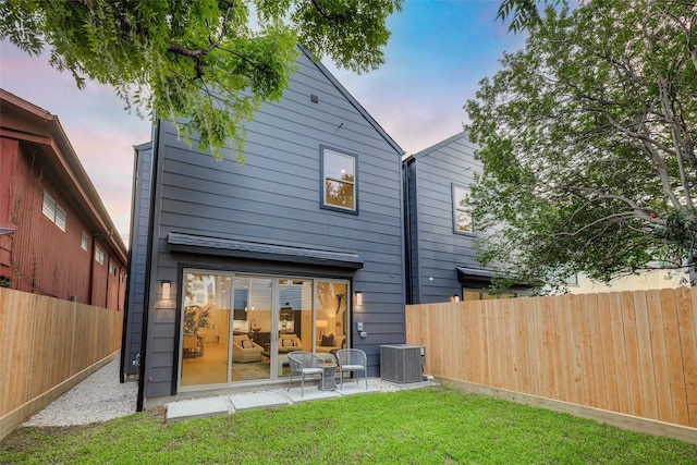 rear view of house with a patio, cooling unit, a lawn, and fence