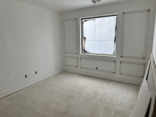 empty room with baseboards and concrete flooring