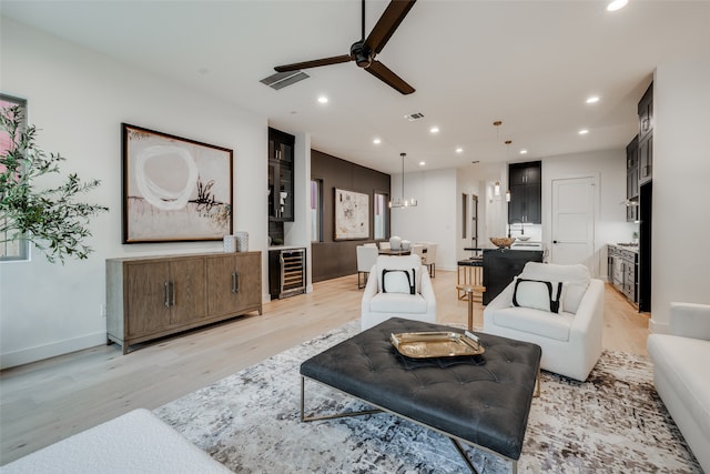 living area with light wood-style floors, recessed lighting, beverage cooler, and visible vents