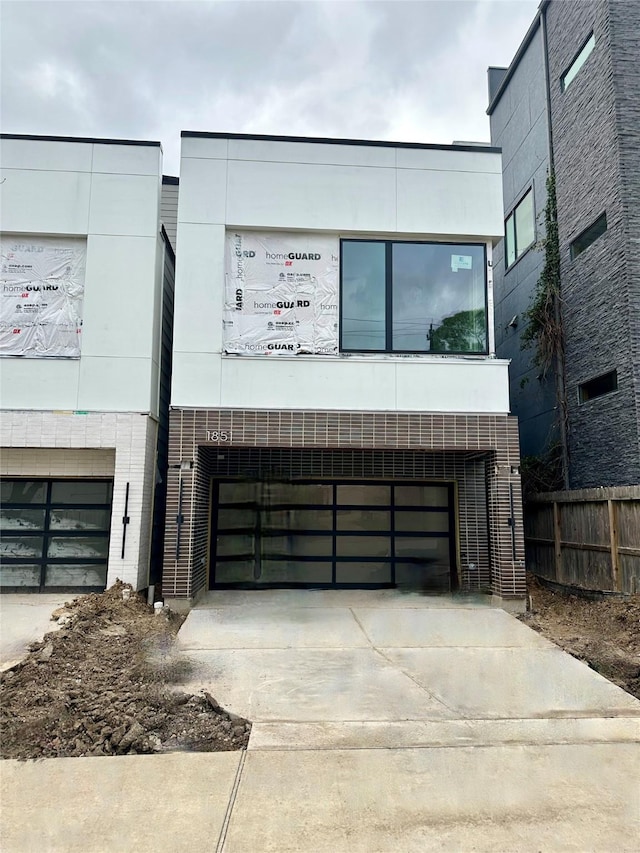 modern home with a garage, concrete driveway, and fence