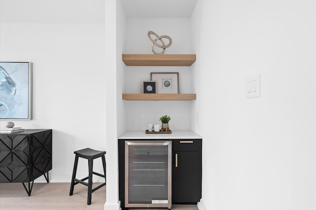 bar featuring beverage cooler and light hardwood / wood-style floors