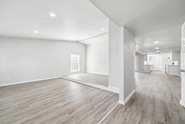 unfurnished room featuring vaulted ceiling and light hardwood / wood-style flooring