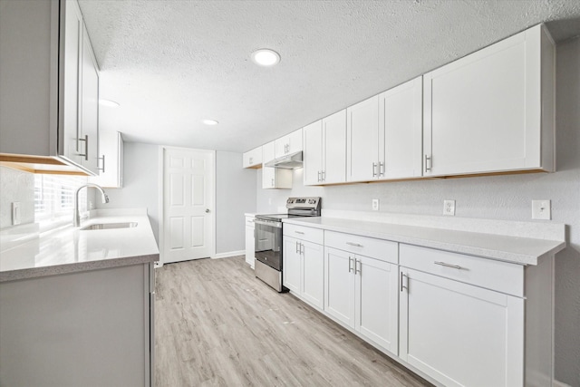 kitchen with sink, white cabinets, stainless steel range with electric stovetop, light hardwood / wood-style floors, and a textured ceiling