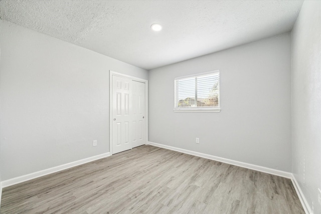 unfurnished room with light hardwood / wood-style flooring and a textured ceiling