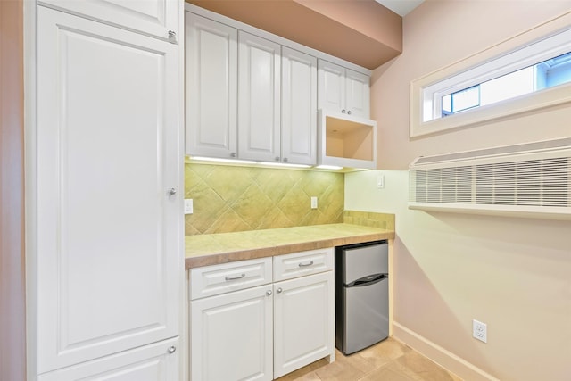 kitchen with white cabinetry, tasteful backsplash, and stainless steel refrigerator