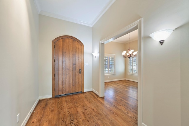 foyer featuring crown molding, an inviting chandelier, and hardwood / wood-style flooring