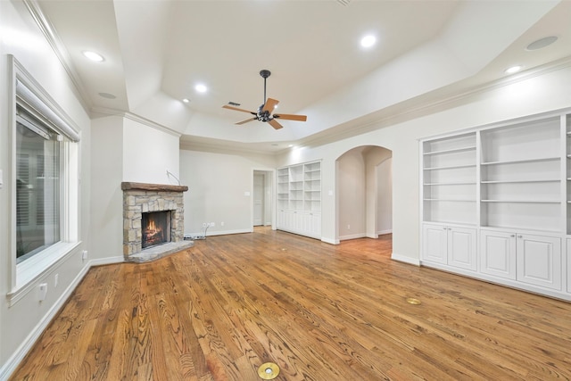 unfurnished living room featuring hardwood / wood-style flooring, ornamental molding, built in features, and a fireplace