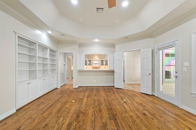 unfurnished living room featuring ceiling fan, ornamental molding, wood-type flooring, and a tray ceiling