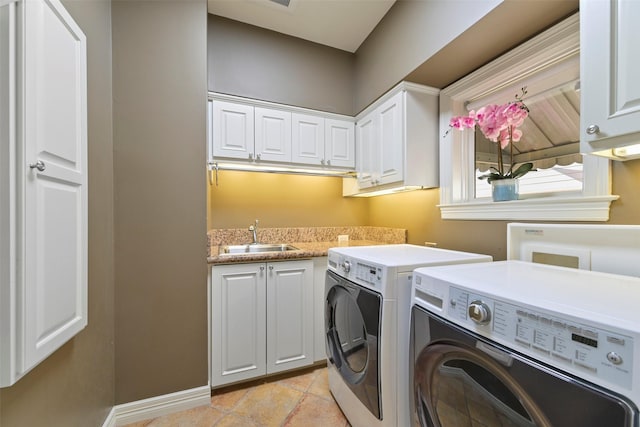 clothes washing area with washer and dryer, sink, light tile patterned floors, and cabinets