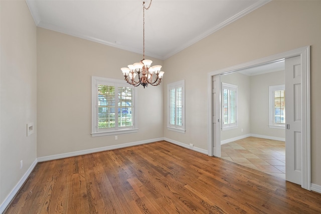 empty room with crown molding, wood-type flooring, and an inviting chandelier