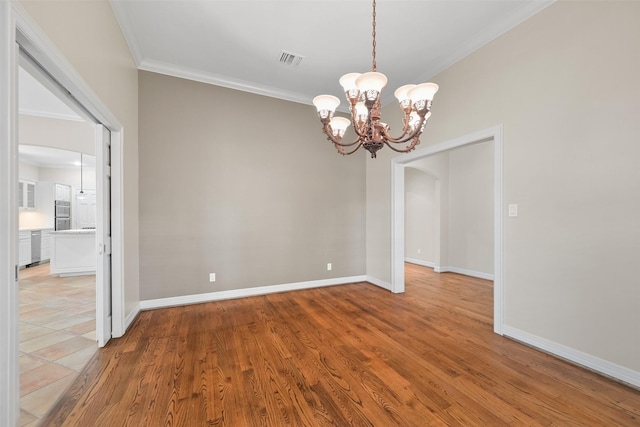 empty room with crown molding, light hardwood / wood-style flooring, and a notable chandelier