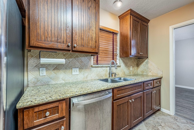 kitchen featuring appliances with stainless steel finishes, tasteful backsplash, sink, light stone countertops, and a textured ceiling