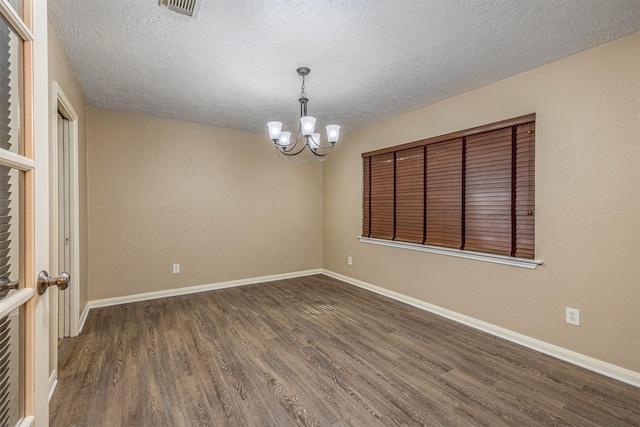 unfurnished room with dark wood-type flooring, a textured ceiling, and an inviting chandelier