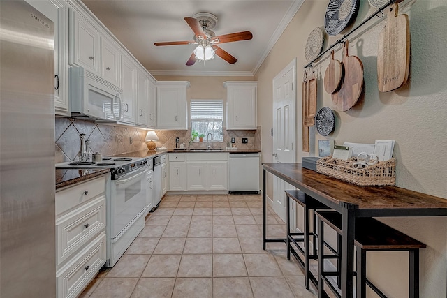 kitchen featuring stainless steel appliances, tasteful backsplash, light tile patterned floors, white cabinets, and crown molding