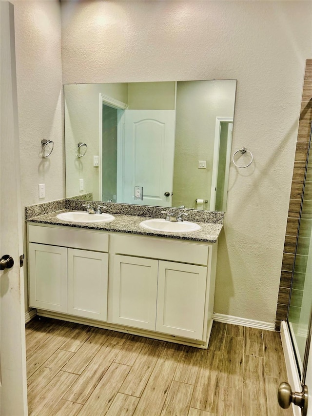 bathroom featuring wood-type flooring, a shower with shower door, and vanity