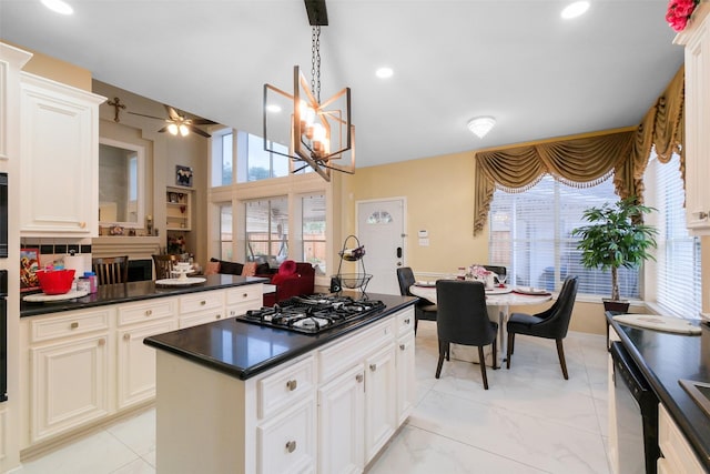 kitchen with ceiling fan with notable chandelier, dishwasher, a kitchen island, decorative light fixtures, and stainless steel gas stovetop