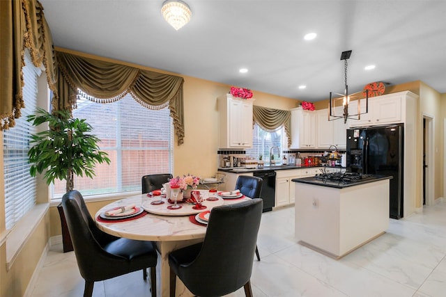 kitchen featuring black dishwasher, stainless steel gas cooktop, white cabinets, a kitchen island, and decorative light fixtures