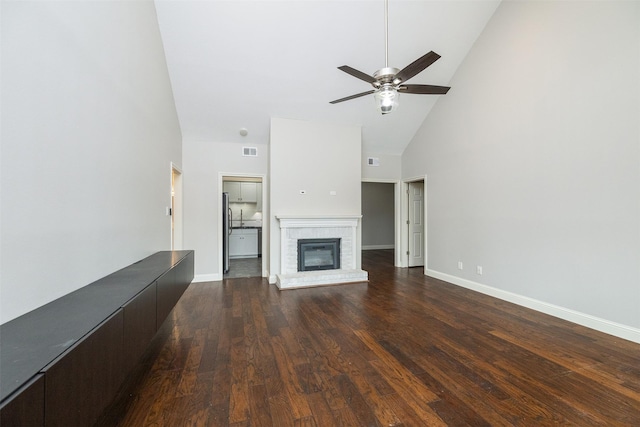 unfurnished living room with dark wood-type flooring, ceiling fan, a fireplace, and high vaulted ceiling