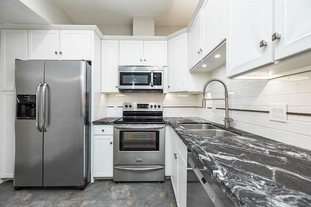 kitchen featuring sink, appliances with stainless steel finishes, dark stone countertops, tasteful backsplash, and white cabinets