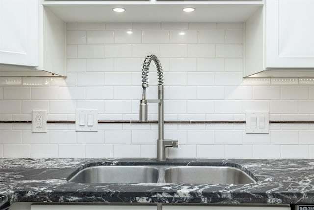 kitchen with sink, dark stone countertops, and white cabinets