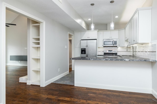 kitchen featuring decorative light fixtures, sink, white cabinets, kitchen peninsula, and stainless steel appliances