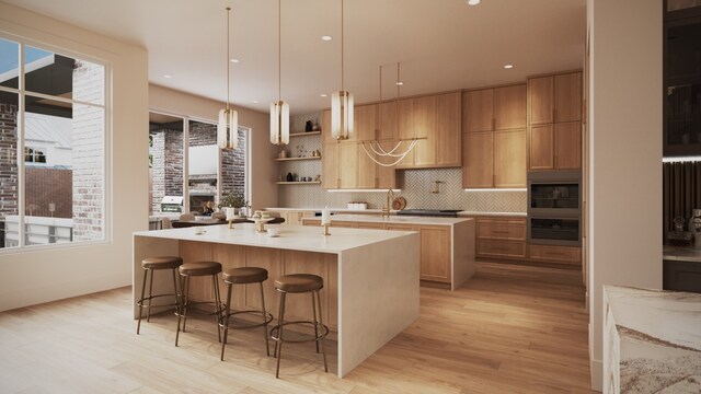 kitchen featuring hanging light fixtures, a kitchen breakfast bar, tasteful backsplash, a center island with sink, and oven