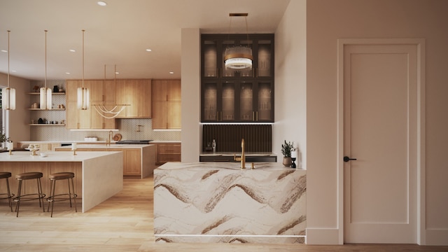 1615 Milford St, Houston, TX 77006 - kitchen featuring light wood-style floors, tasteful backsplash, a kitchen bar, decorative light fixtures, and recessed lighting