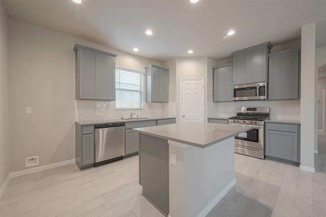 kitchen with gray cabinets, a kitchen island, appliances with stainless steel finishes, and light wood-type flooring