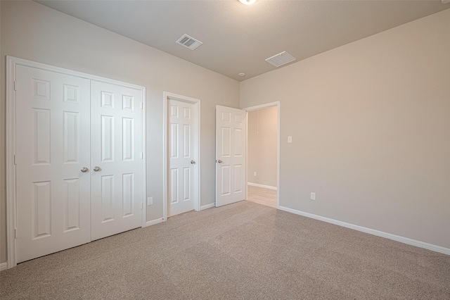 unfurnished bedroom featuring light carpet and two closets