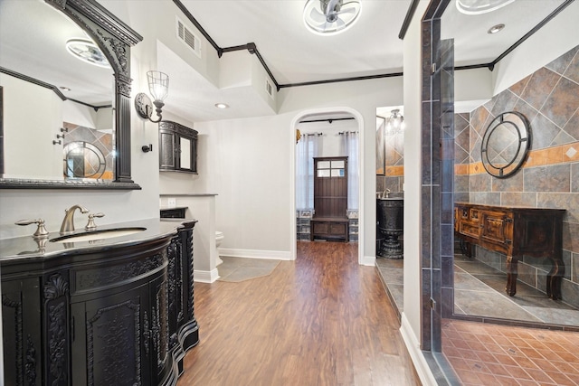 bathroom featuring toilet, a shower, wood-type flooring, ornamental molding, and vanity