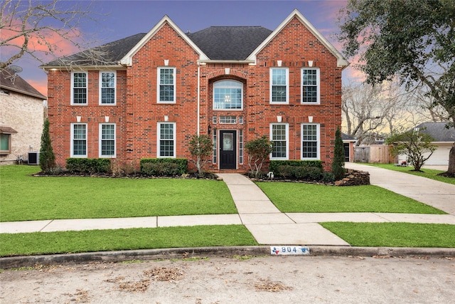 view of front of property featuring a lawn and central air condition unit