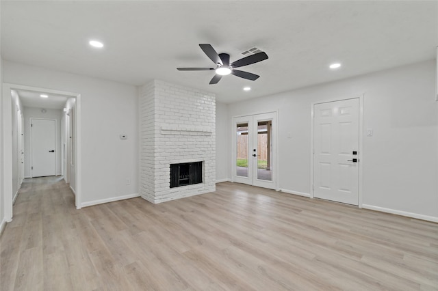 unfurnished living room featuring a fireplace, light hardwood / wood-style flooring, french doors, and ceiling fan