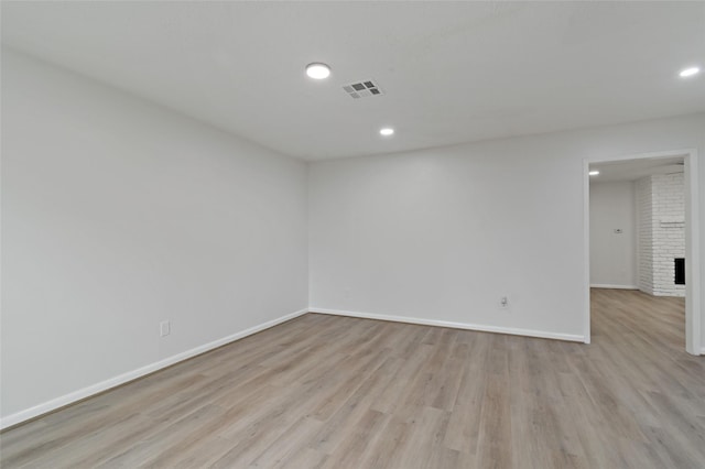 empty room with a fireplace and light hardwood / wood-style floors