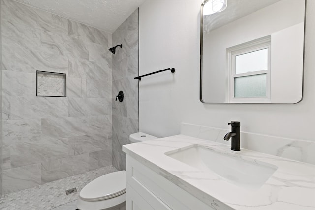 bathroom featuring vanity, tiled shower, and toilet