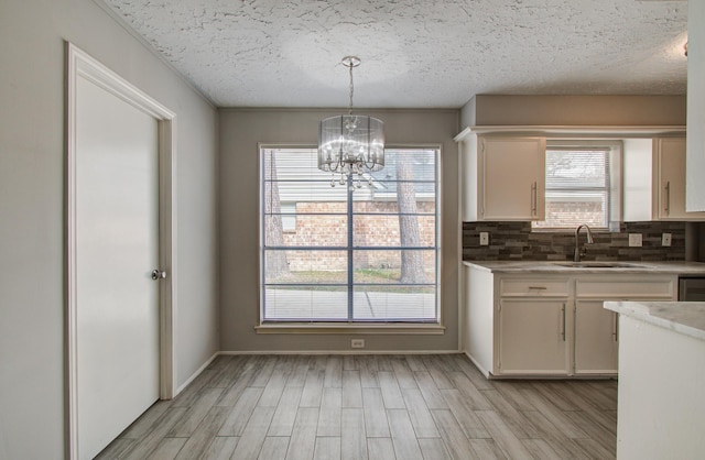 kitchen featuring sink, white cabinetry, hanging light fixtures, an inviting chandelier, and light wood-type flooring