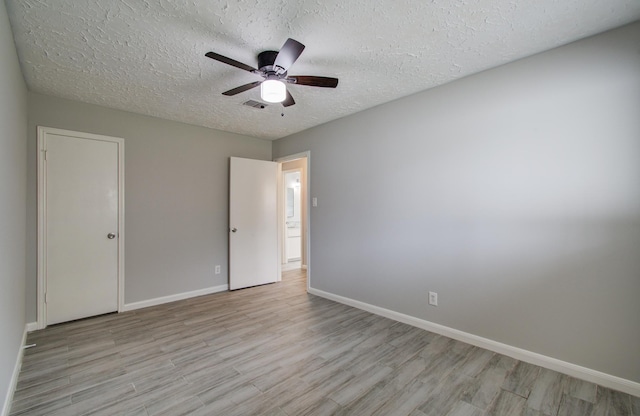 unfurnished room featuring ceiling fan, a textured ceiling, and light wood-type flooring