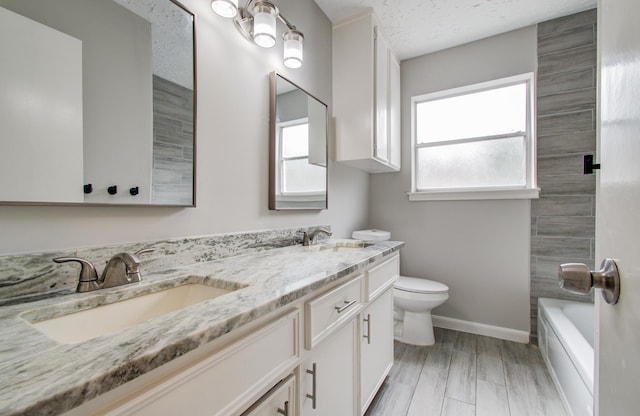 full bathroom with vanity, plenty of natural light, a textured ceiling, and toilet