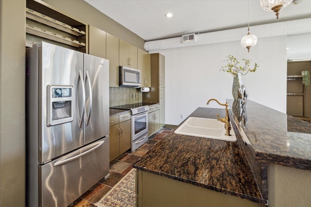 kitchen with stainless steel appliances, cream cabinets, sink, and dark stone counters