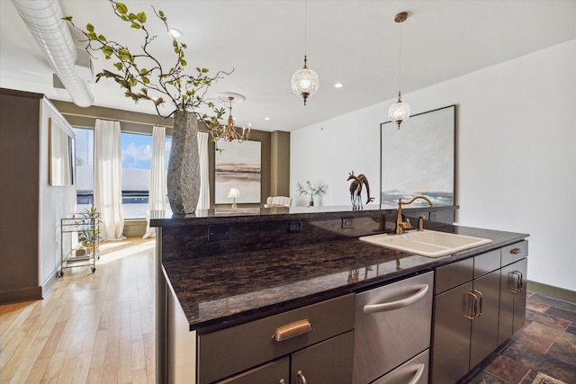 kitchen with sink, dark stone countertops, a water view, an island with sink, and decorative light fixtures