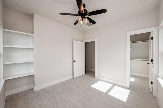 unfurnished bedroom with ceiling fan, a spacious closet, and a closet